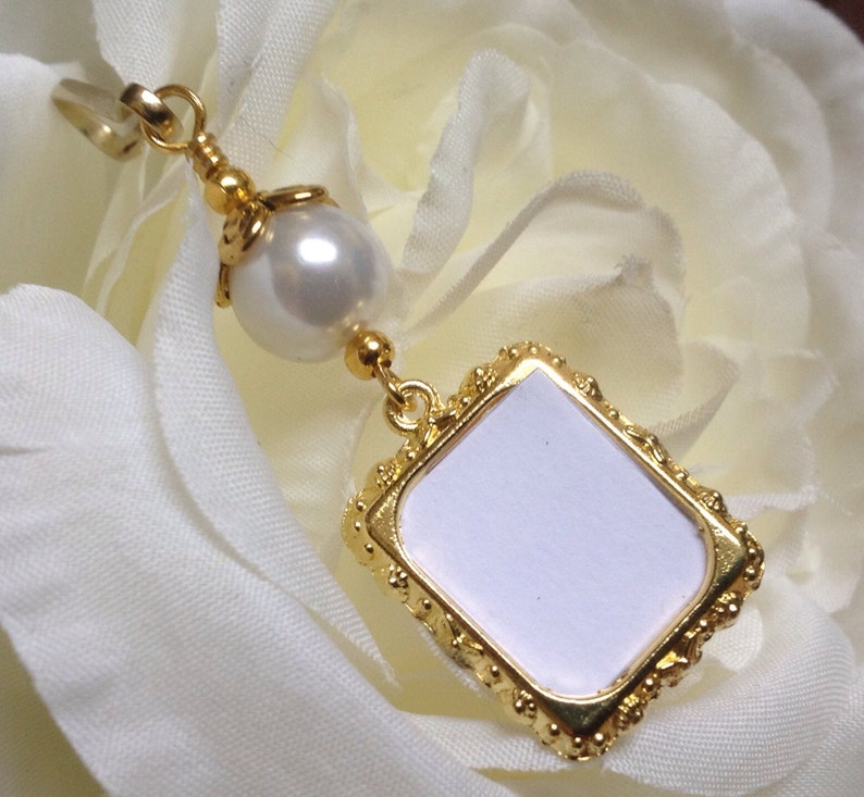 May include: Gold-toned picture frame charm with a white pearl and a gold loop for attaching to a necklace or bracelet.