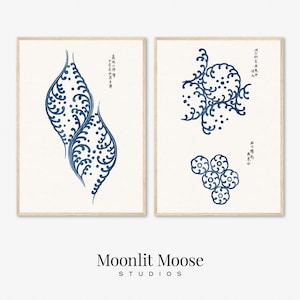 May include: Two framed prints with blue and white Japanese-inspired designs. The left print features a stylized wave pattern, while the right print features a circular pattern with dots. Both prints include Japanese text.