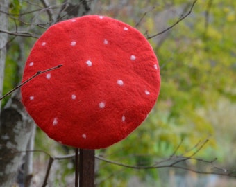 May include: A red felt beret with white polka dots. The beret is sitting on a wooden stick.