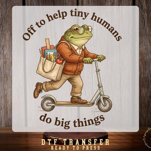May include: A graphic print featuring a frog wearing glasses, a brown cardigan, and tan trousers, riding a scooter. The frog carries a tote bag filled with school supplies. The text reads: Off to help tiny humans do big things.