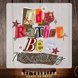 May include: A decorative square with the words "I'd Rather Be Thrifting" in a collage style. The design features various colors, patterns, and embellishments, including leopard print, stars, and floral accents. The phrase "DTF TRANSFER READY TO PRESS" is at the bottom.