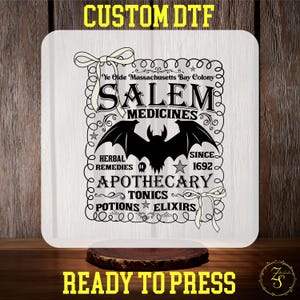 May include: A white square sign with the text "CUSTOM DTF" at the top and "READY TO PRESS" at the bottom. The sign features a black bat and the words "SALEM MEDICINES" with other text, including "HERBAL REMEDIES" and "APOTHECARY".