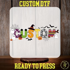 May include: A white, square-shaped design featuring the word "CUSTOM" in colorful, Halloween-themed letters. The design includes pumpkins, bats, ghosts, witch hats, and spiderwebs. The text "CUSTOM DTF" and "READY TO PRESS" are in yellow.