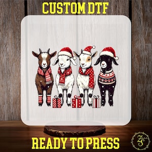 May include: A white square with four cartoon goats wearing Santa hats, red scarves, and sweaters. Each goat stands in front of a red gift box. The text "CUSTOM DTF" and "READY TO PRESS" are in yellow.