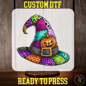 May include: A colorful witch hat design with a patchwork pattern in purple, green, orange, and pink. A carved pumpkin is centered on the hat. The text "CUSTOM DTF" and "READY TO PRESS" are displayed in yellow.