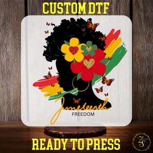May include: A white square with a design featuring a black silhouette of a woman's face with flowers and butterflies. The words "Juneteenth Freedom" are written in gold script. The text "CUSTOM DTF" and "READY TO PRESS" are in yellow.