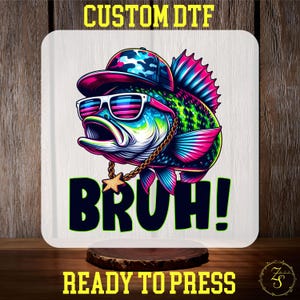 May include: A colorful, cartoon-style fish wearing a backwards baseball cap, sunglasses, and a gold chain. The fish is pink, blue, and green with black outlines. The text "BRUH!" is written below the fish in black letters.
