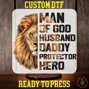 May include: A white sublimation design with a lion's head and the text "Man of God, Husband, Daddy, Protector, Hero". The design is ready to press.