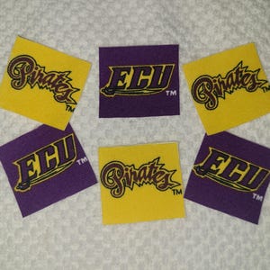 May include: Six square fabric patches with the logos of East Carolina University. The patches alternate between yellow and purple. The yellow patches have the word "Pirates" in a script font. The purple patches have the letters "ECU".