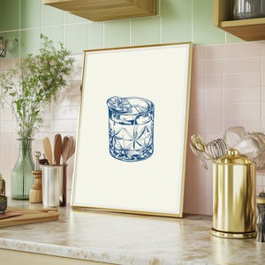 May include: A framed illustration of a blue cocktail glass with ice and a lime wedge. The glass is on a white background.