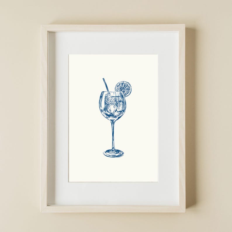 May include: A framed illustration of a blue cocktail with ice cubes and a lemon slice in a tall glass with a straw. The illustration is on a white background.