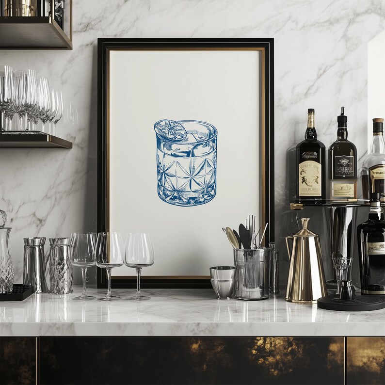 May include: A blue and white illustration of a cocktail in a rocks glass with a lime wedge on top. The illustration is framed and hanging on a wall above a bar counter.