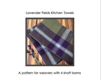 Op de afbeelding: Geweven keukendoeken met patronen in groen, paars en blauw, opgevouwen op een houten oppervlak. De afbeelding bevat de tekst "Lavender Fields Kitchen Towels" en "A pattern for weavers with 4 shaft looms."