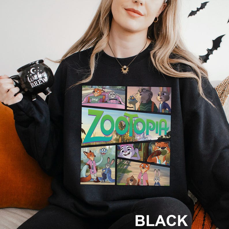 May include: Black sweatshirt featuring a colorful graphic from the animated film "Zootopia." The design includes various characters and the film's title in a vibrant font. The word "BLACK" is printed at the bottom.