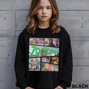 May include: Black sweatshirt featuring a colorful graphic from the animated movie "Zootopia." The design includes various characters and the film's title in green and blue. The sweatshirt is a crew neck style.