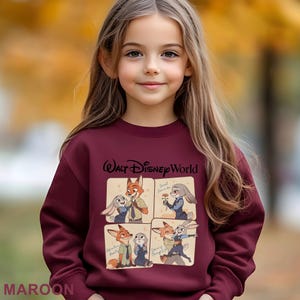 May include: A maroon sweatshirt with a Disney's Zootopia design. The graphic features Nick Wilde and Judy Hopps in four panels, with "Walt Disney World" above. The word "MAROON" is printed at the bottom. The sweatshirt is worn by a person.
