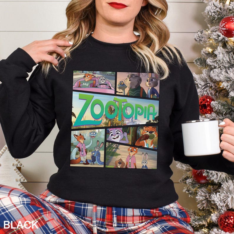 May include: Black crewneck sweatshirt featuring a colorful graphic from the animated film "Zootopia." The design includes the film's title in green and images of the characters. The word "BLACK" is printed at the bottom.