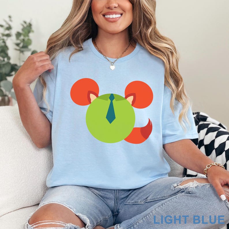 May include: Light blue t-shirt featuring a cartoon mouse design with a green face, orange ears, and a blue tie. The shirt is made of a soft material and is suitable for casual wear. The text "LIGHT BLUE" is printed at the bottom.