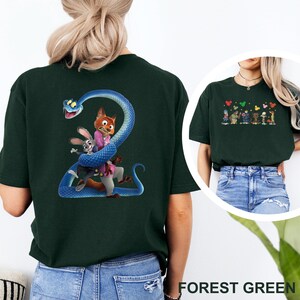 K&ouml;nnte beinhalten: Forstgr&uuml;nes T-Shirt mit einem farbenfrohen Grafikdesign von Zeichentrickfiguren. Das Design zeigt eine blaue Schlange, die sich um einen Fuchs, ein Kaninchen und andere Charaktere windet. Das T-Shirt ist aus weichem Material.