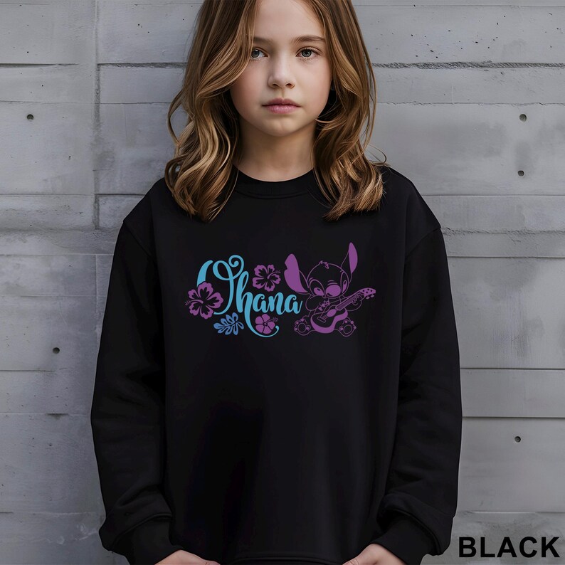 May include: Black sweatshirt featuring the word "Ohana" in blue and purple script, with floral accents and a cartoon character playing a ukulele. The word "BLACK" is printed in white at the bottom right.