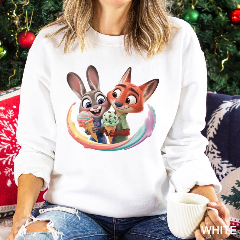 May include: White sweatshirt featuring a colorful cartoon image of a bunny and fox holding ice cream cones. The bunny is gray and the fox is orange. The ice cream cones have pastel colors. The sweatshirt is a crew neck style.