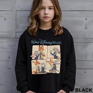 May include: Black sweatshirt with a Walt Disney World logo and a four-panel graphic of Zootopia characters. The graphic includes the text "Sweet Surrender", "Adventure Awaits", and "Dancing Through Life".