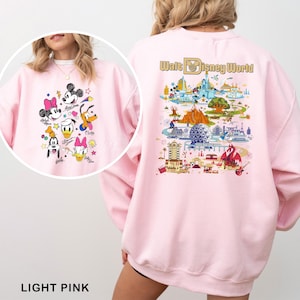 May include: Light pink sweatshirt featuring a colorful graphic of Disney characters on the front and a Walt Disney World map design on the back. The sweatshirt has long sleeves and a crew neck. The text "LIGHT PINK" is at the bottom.
