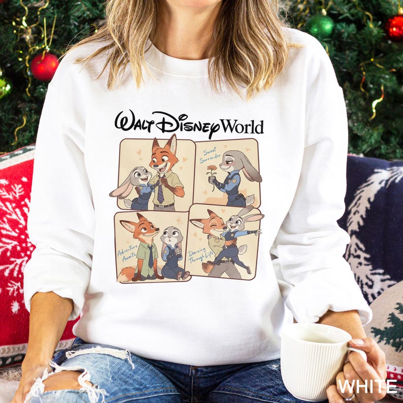 May include: White sweatshirt with a Walt Disney World graphic. The design features cartoon images of Nick Wilde and Judy Hopps, with the phrases "Sweet Surrender", "Adventure Awaits", and "Dancing Through Life". The sweatshirt is made of a soft material.