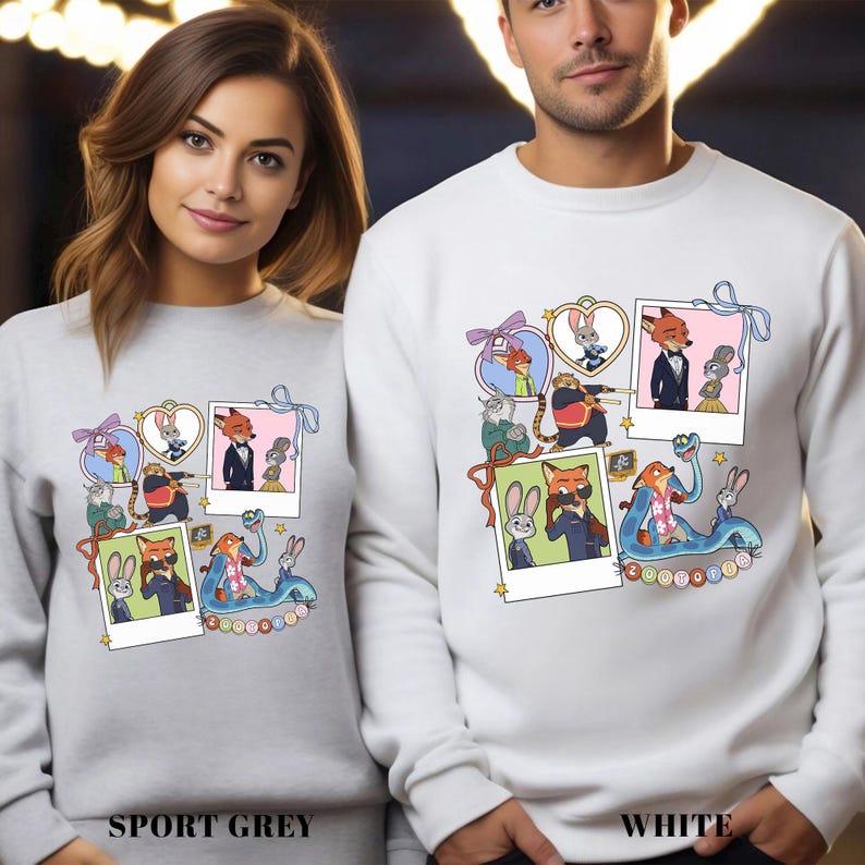 May include: Sport grey and white sweatshirts featuring a colorful cartoon collage of characters. The design includes framed images of a fox, bunny, and other animals. The word "Zootopia" is visible on the design.