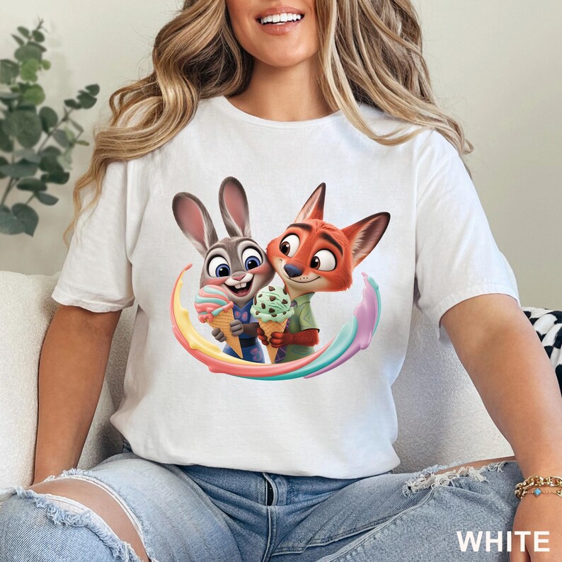 May include: White t-shirt featuring a colorful graphic of Judy Hopps and Nick Wilde from Zootopia, each holding an ice cream cone. The design includes a rainbow-colored swirl. The word "WHITE" is printed in the lower right corner.