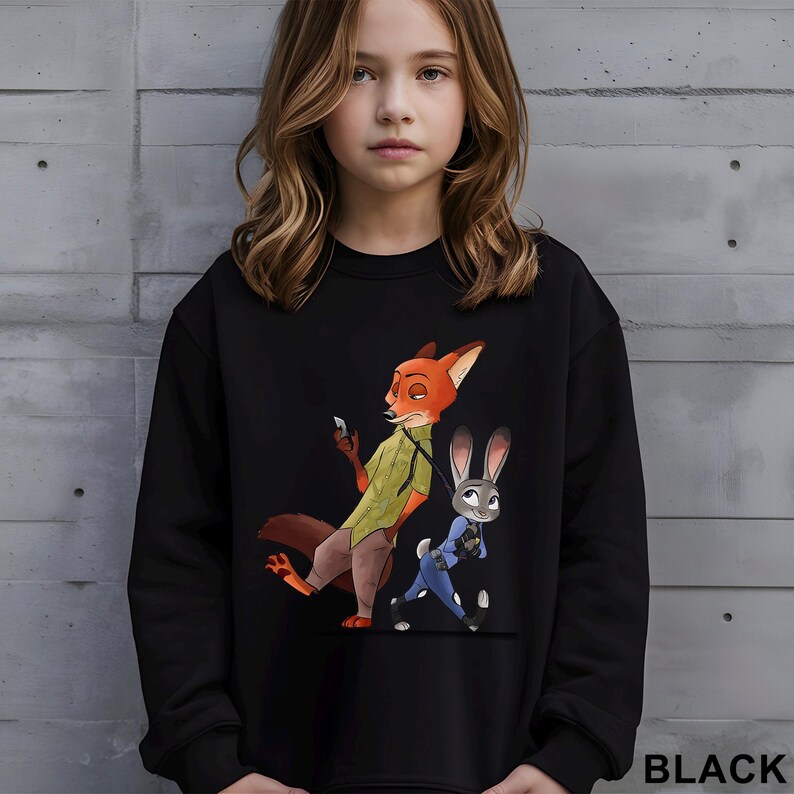May include: Black sweatshirt featuring a cartoon illustration of Nick Wilde and Judy Hopps from Zootopia. Nick is a fox wearing a green shirt and Judy is a rabbit in a blue police uniform. The word "BLACK" is printed at the bottom.