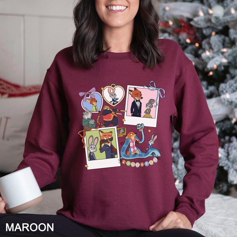 May include: Maroon sweatshirt featuring a collage of cartoon characters in polaroid-style frames. The design includes images of a fox, a rabbit, and other characters. The word "MAROON" is printed at the bottom of the sweatshirt.