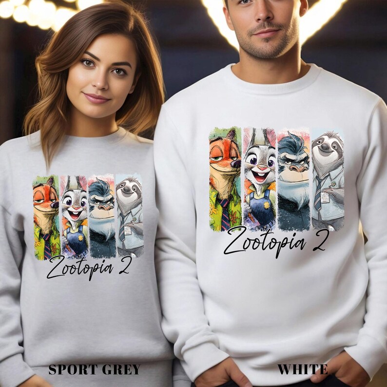 Puede incluir: Sudaderas grises deportivas y blancas con un gr&aacute;fico colorido de personajes de Zootopia 2. El dise&ntilde;o incluye a Nick Wilde, Judy Hopps y otros personajes. El texto "Zootopia 2" est&aacute; escrito en una fuente de gui&oacute;n debajo.
