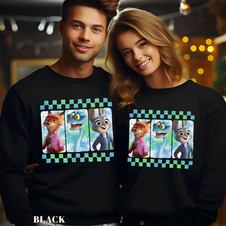 May include: Black sweatshirts featuring a colorful graphic of cartoon characters. The graphic includes a fox in a pink shirt, a blue snake, and a rabbit in a blue jacket. The design is framed by a checkered pattern in green and blue.