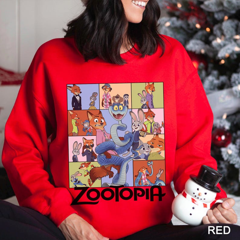 May include: A red sweatshirt featuring a colorful graphic of characters from the animated film "Zootopia." The design includes various animal characters in a grid layout, with the film's title in black at the bottom. The word "RED" is in the bottom right corner.