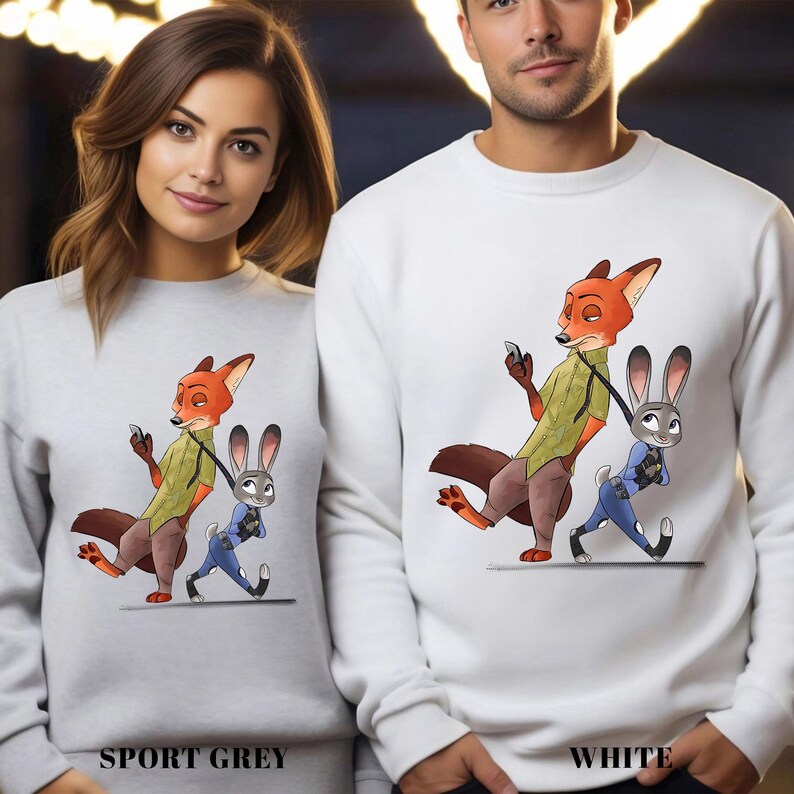 May include: Sport grey and white sweatshirts featuring a cartoon fox and bunny design. The fox is wearing a green shirt and holding a phone, while the bunny is in a police uniform. The text "SPORT GREY" and "WHITE" are printed at the bottom.