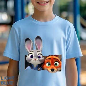 May include: Light blue t-shirt featuring Judy Hopps and Nick Wilde from Zootopia. The graphic shows the characters' faces peeking out from a torn rectangle. The text "LIGHT BLUE" is printed at the bottom left.