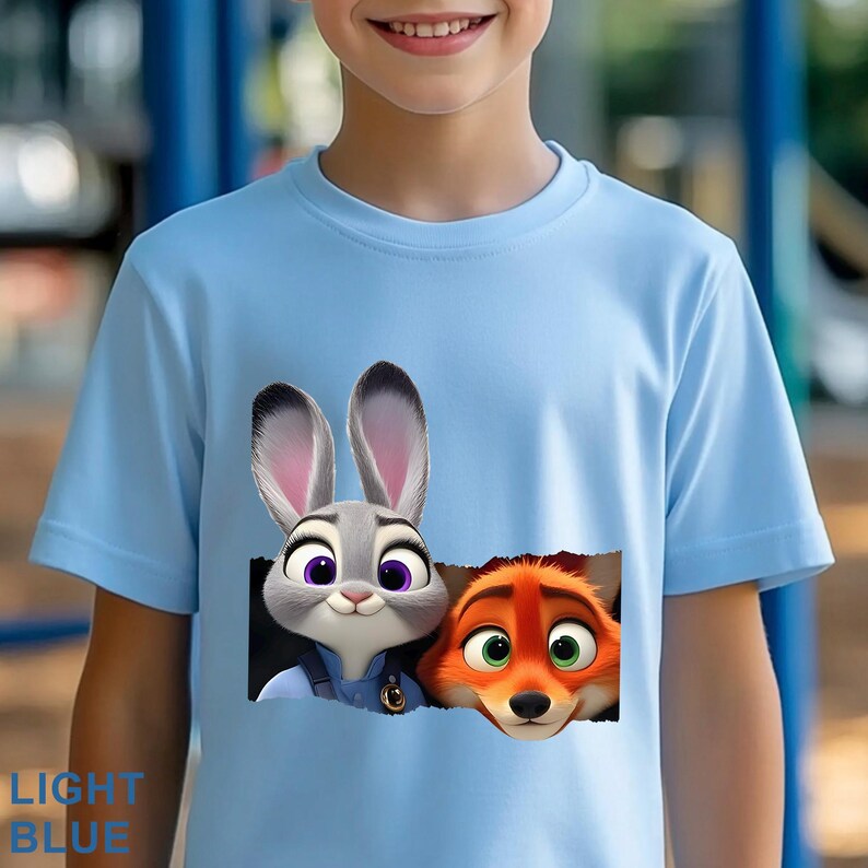 May include: Light blue t-shirt featuring Judy Hopps and Nick Wilde from Zootopia. The graphic shows the characters' faces peeking out from a torn rectangle. The text "LIGHT BLUE" is printed at the bottom left.