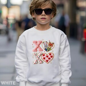 May include: White sweatshirt with an embroidered design featuring the letters "XO", a heart, and cartoon characters Judy Hopps and Nick Wilde. The design includes pink, red, and gold accents. The word "WHITE" is printed at the bottom.