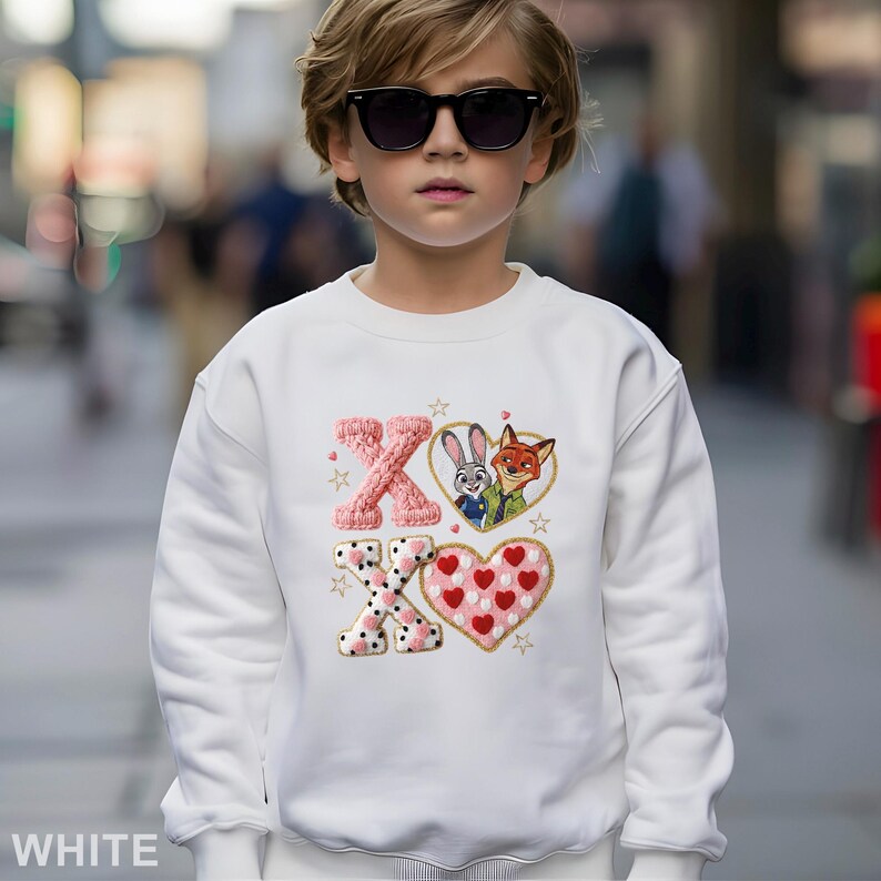 May include: White sweatshirt with an embroidered design featuring the letters "XO", a heart, and cartoon characters Judy Hopps and Nick Wilde. The design includes pink, red, and gold accents. The word "WHITE" is printed at the bottom.