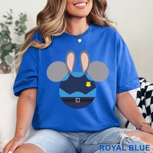 May include: Royal blue t-shirt featuring a cartoon design of a police officer bunny. The design includes a blue uniform, a yellow badge, and gray bunny ears. The text "ROYAL BLUE" is at the bottom of the image.