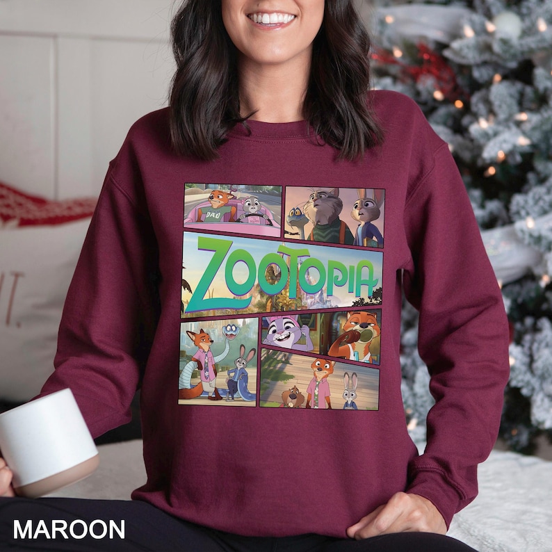 May include: Maroon sweatshirt featuring a comic strip design with characters and the title "Zootopia". The graphic includes various scenes from the animated movie. The sweatshirt is a solid maroon color.