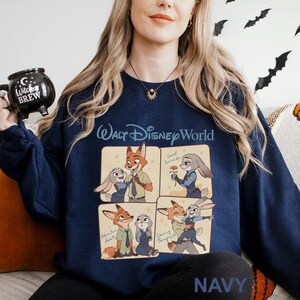 May include: Navy blue sweatshirt with a four-panel illustration of Zootopia characters. The words "Walt Disney World" are printed in white across the chest. The word "NAVY" is printed in white at the bottom of the sweatshirt.