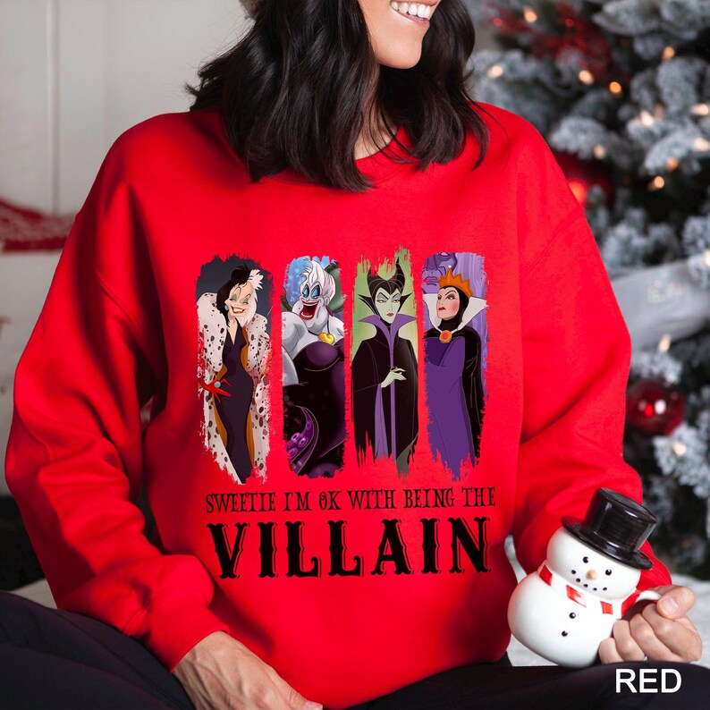 May include: Red sweatshirt featuring four cartoon villain characters. The text "Sweetie I'm OK with being the Villain" is printed below the characters. The word "RED" is printed in the bottom right corner.