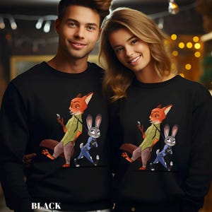 May include: Black sweatshirts featuring a cartoon fox and rabbit character design. The fox is orange and wearing a green shirt and brown pants. The rabbit is gray and wearing a blue uniform. The word "BLACK" is printed at the bottom.
