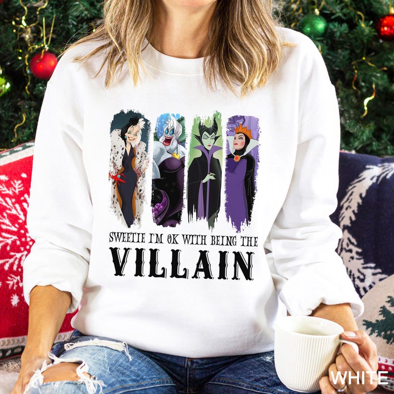 May include: White sweatshirt featuring four cartoon villain characters with the text "Sweetie I'm ok with being the Villain". The characters are in vertical rectangular panels with different color backgrounds.