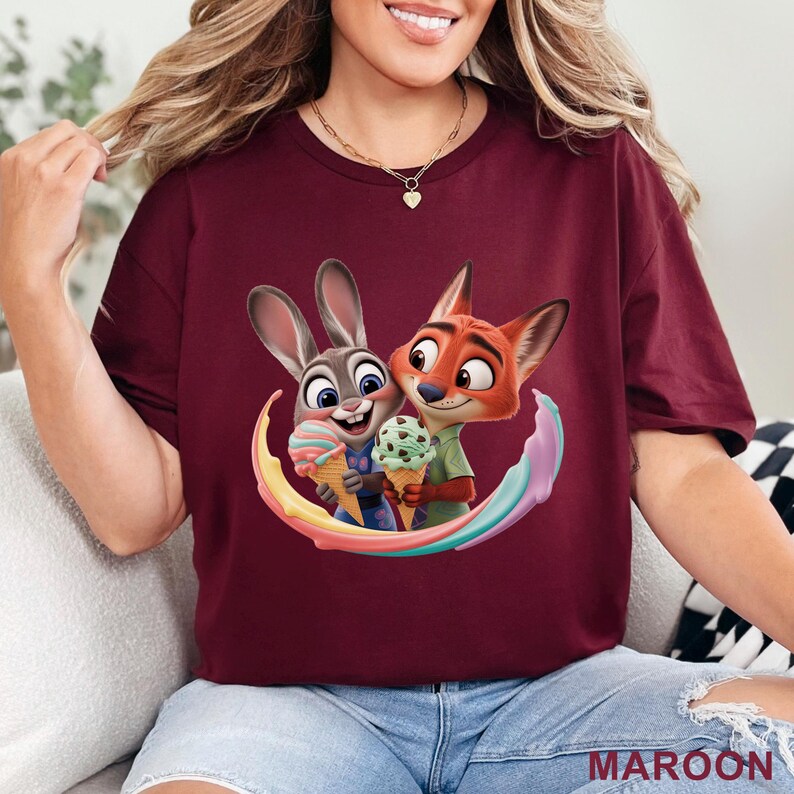 May include: Maroon t-shirt featuring a colorful graphic of Judy Hopps and Nick Wilde from Zootopia, each holding ice cream cones. The design includes a rainbow-colored swirl. The word "MAROON" is printed at the bottom.