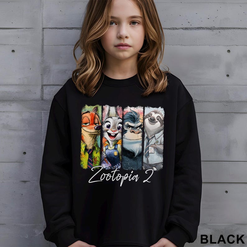 Puede incluir: Sudadera negra con un gr&aacute;fico colorido de personajes de Zootopia, incluyendo un zorro, un conejo, un gorila y un perezoso. El texto "Zootopia 2" est&aacute; escrito en blanco debajo de los personajes. La palabra "BLACK" est&aacute; impresa en la esquina inferior derecha.