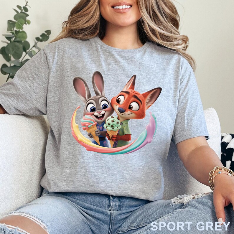 May include: Sport grey t-shirt featuring a colorful graphic of two cartoon characters, a rabbit and a fox, holding ice cream cones. The characters are surrounded by a rainbow arc. The text "SPORT GREY" is printed at the bottom right.