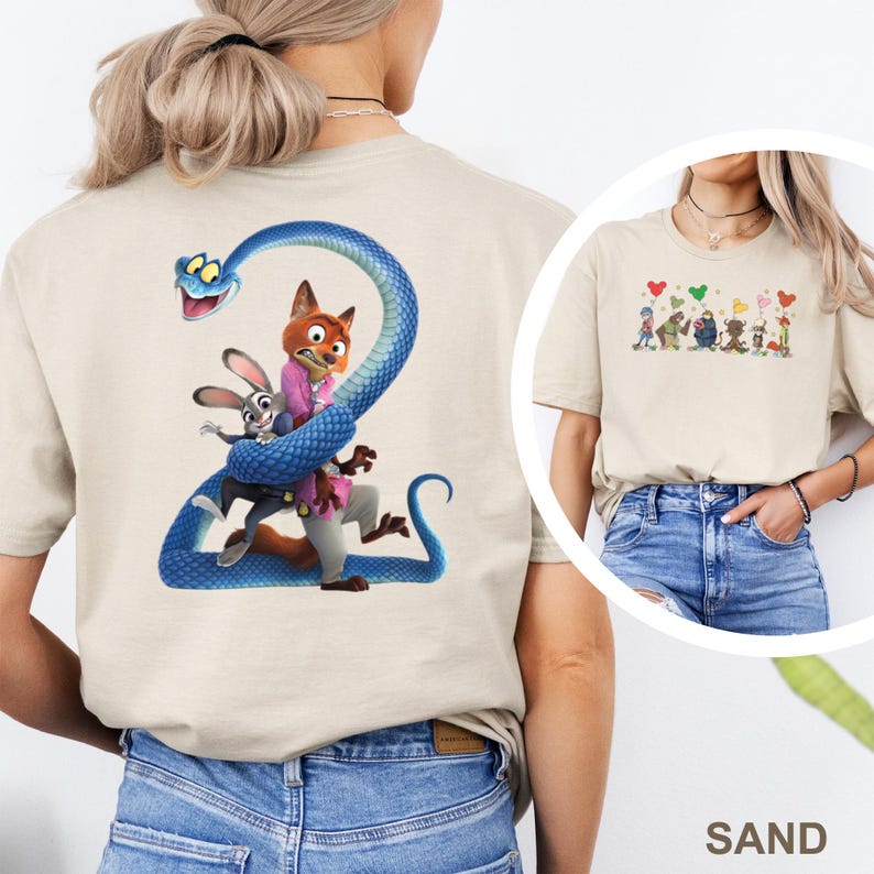 K&ouml;nnte beinhalten: Sandfarbenes T-Shirt mit einer farbenfrohen Grafik von Charakteren aus einem beliebten Animationsfilm. Auf der R&uuml;ckseite des Shirts ist eine blaue Schlange zu sehen, die sich um einen Fuchs, ein Kaninchen und eine Figur windet. Die Vorderseite hat eine kleinere Grafik von Charakteren und Herzen.